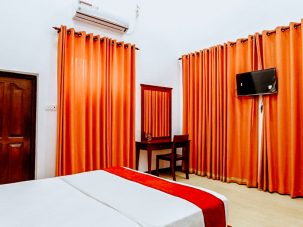 The comfortable bed in the Chrysanthemum Room at Flamingo Villa in Jaffna, featuring elegant linens, cozy pillows, and inviting decor for a restful night's sleep.