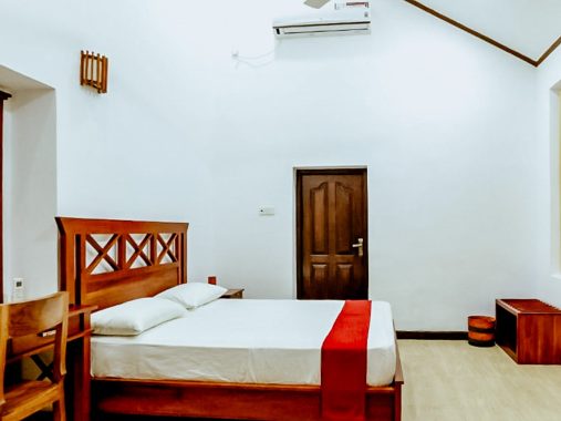 The spacious Gloriosa Room at Flamingo Villa in Jaffna, featuring air conditioning, a wardrobe, a private bathroom with a shower and bidet, a tiled floor, and a flat-screen TV with cable channels. The room includes a comfortable double bed for a relaxing stay.